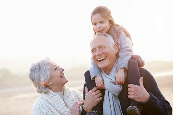 Grandparents with grandchild riding on grandfathers' shoulders